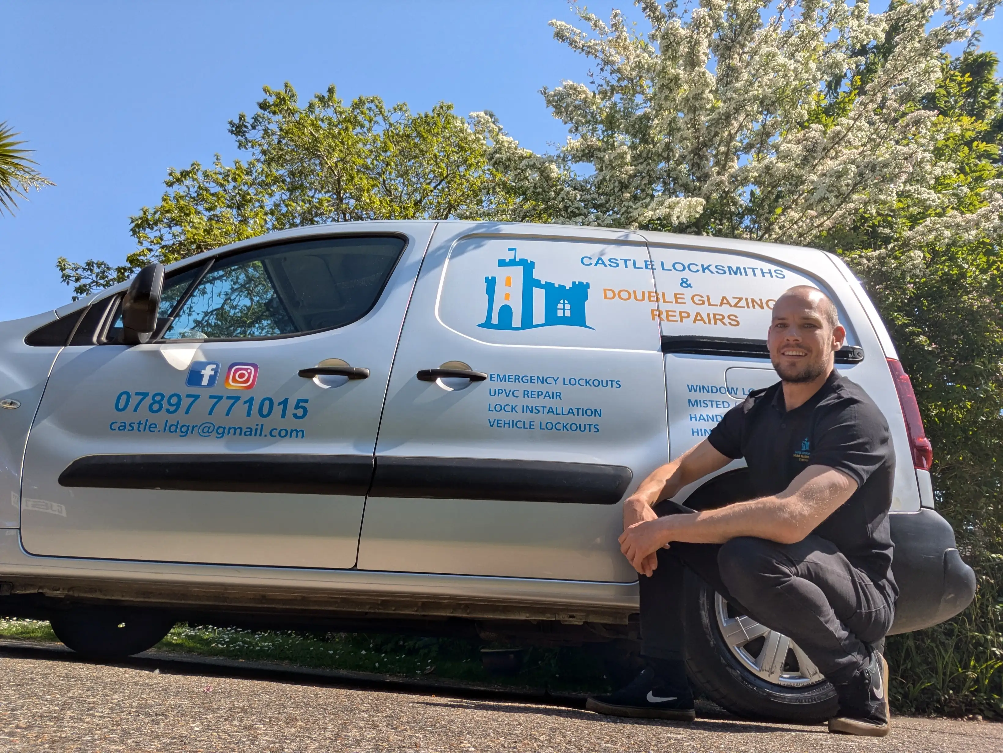A locksmith crouches next to a branded van for Castle Locksmiths & Double Glazing Repairs on a sunny day, with contact information and services displayed on the vehicle.
